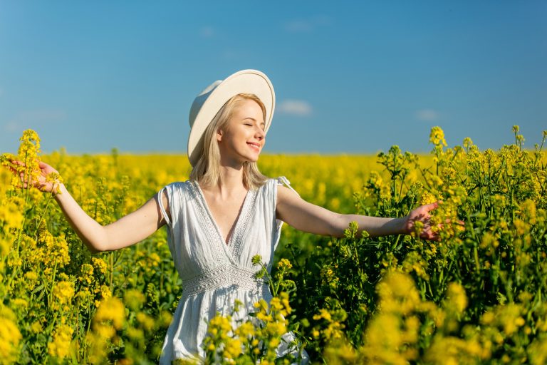 Beautiful woman in dress in rapeseed field